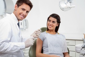 Happy Male Dentist Holding Thread While Patient Looking At Him