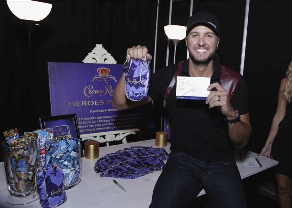 Musician Luke Bryan stuffs a Crown Royal CAMO care package to be sent to troops backstage at the 2015 CMT Awards at Bridgestone Arena on June 10, 2015 in Nashville, Tennessee. (Photo by Anna Webber/Getty Images for Crown Royal) 