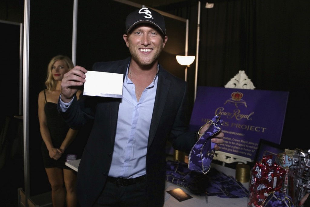 Songwriter Cole Swindell stuffs a Crown Royal CAMO care package to be sent to troops backstage at the 2015 CMT Awards at Bridgestone Arena on June 10, 2015 in Nashville, Tennessee. (Photo by Anna Webber/Getty Images for Crown Royal) 